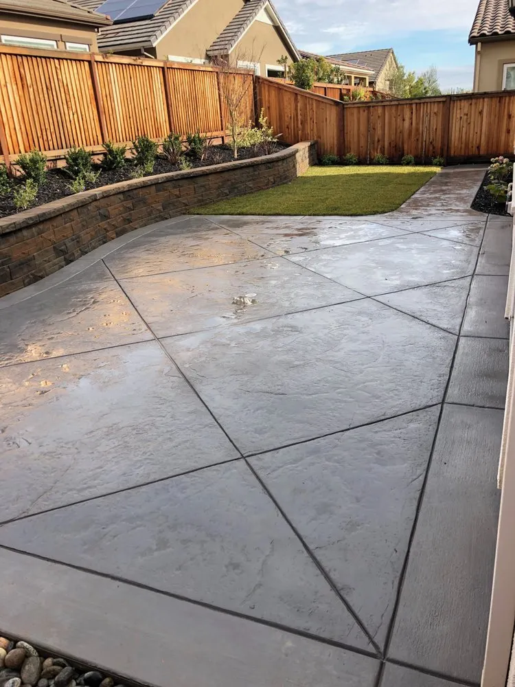 Picture of Sunlight reflects off a meticulously crafted stamped concrete patio, seamlessly blending with the landscaped gardenâ€”an ARP Hardscape signature, recognized for expertise and quality. Copyright ©2025 Diamond Certified Resource - ARP Hardscape